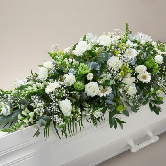Hvit blomsterdekorasjon på en hvit kiste