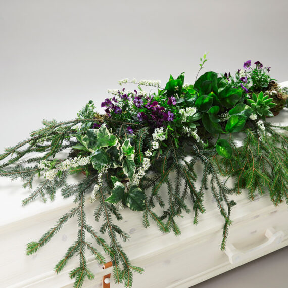 Grønn blomsterdekorasjon på en hvit kiste
