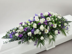 Hvit og blå blomsterdekorasjon på en hvit kiste