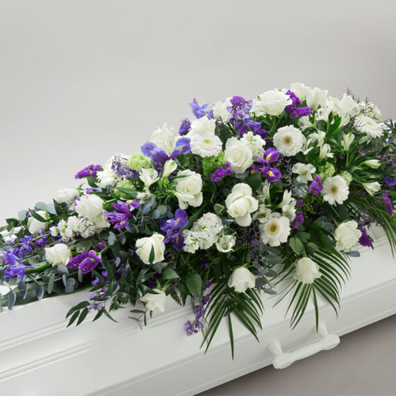 Hvit og blå blomsterdekorasjon på en hvit kiste