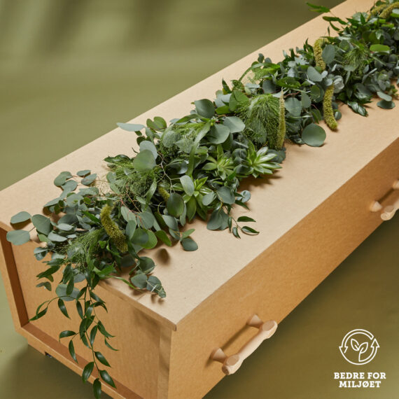 En blomsterdekorasjon på toppen av en kiste av diverse grønne planter.