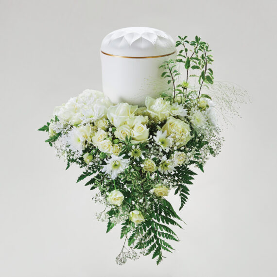 En blomsterdekorasjon i hvite farger med en urne plassert på toppen.